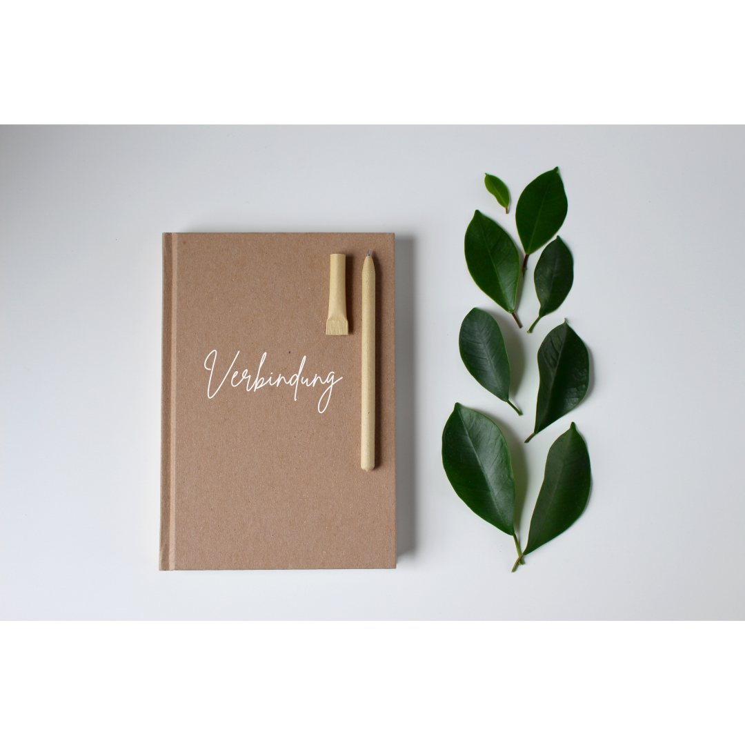 Notizbuch auf dem Verbindung steht, mit grünen Blättern als Dekoration